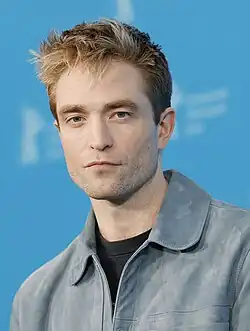 Robert Pattinson staring at the camera; the background is completely blue