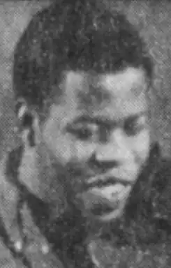 A young Black man, smiling, with a violin under his chin