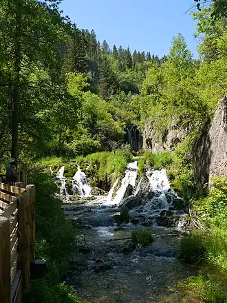 An image of a lush, green waterfall, mid-day