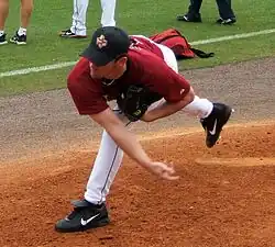 right-handed pitcher wearing a red Astros uniform throws a baseball from a pitching mound.