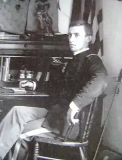 black & white image of a man sitting by a writing desk