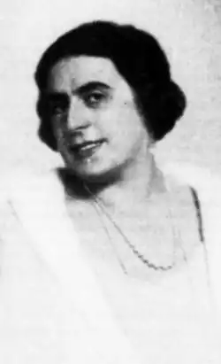 A smiling woman with fair skin and dark hair and eyes, wearing white