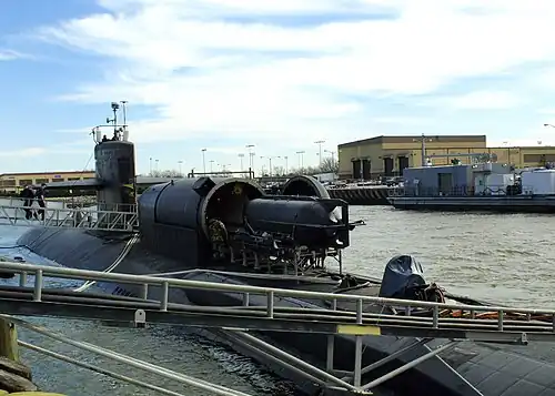 A SEAL Delivery Vehicle (SDV) is loaded aboard the Los Angeles-class fast attack submarine USS&nbsp;Dallas. A Dry Deck Shelter (DDS) is attached to the submarine's forward escape trunk to provide a dry environment for Navy Seals to prepare for special warfare exercises or operations. DDS is the primary supporting craft for the SDV