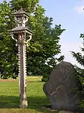 A roofed pole near Savarina village, Mažeikiai district, Lithuania. Note snake motif of roof "supports."