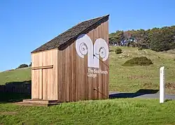 A wooden asymmetrical, bran-like structure at the entrance to the Sea Ranch Lodge, with a white Sea Ranch Lodge logotype painted on it