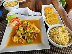Garlic shrimp with okra and carrot, served with pumpkin rice and tostones.