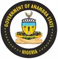 A circular seal with the words "Government of Anambra State" on the top and "Nigeria" on the bottom. In the center, an eagle with a stick of fire stands on an illustrated bridge above the blue water. The water is above two trees. Green ornaments and sun flowers encircles the seal and guided by two horns.