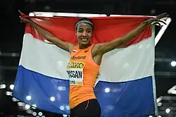 Hassan celebrates and holds a Dutch flag behind her.
