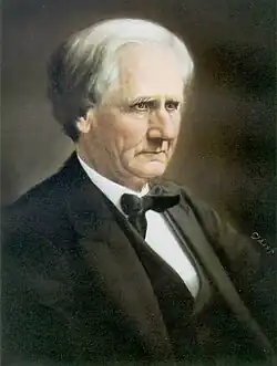 A man in middle age with a black suit and bowtie