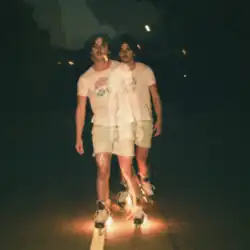 A curly haired man in his 20s rollerblading with fire in the night skies with a photo effect applied