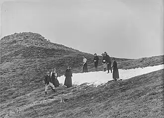 Some people from the 1800s looking fancy on some snow on top of a mountain