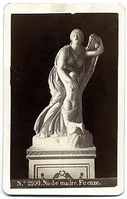Black and white image of a marmor sculpture of a bowing woman with a child nestling in her lap