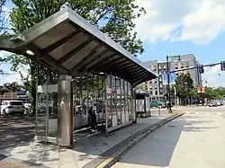A large bus stop shelter made of silver metal and glass