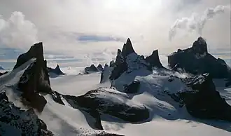 Photograph of a barren mountainscape, with snow surrounding black peaks