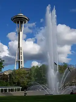 In this photograph, the "super shooters" installed by WET Design in 1995 are in operation and the water jets are reaching their peak height of approximately 120 feet (37&nbsp;m). The ground level perspective creates an illusion the jet is nearly as tall as the Space Needle, shown in the background.