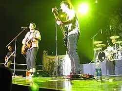 Several man performing onstage playing and singing into a microphone