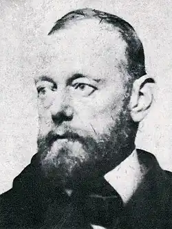 head and shoulders portrait of a middle-aged man with a beard wearing a striped jacket