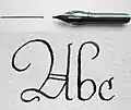 A steel nib with a sample of writing (A b c: the ascender of the "b" is an example of a pothook)