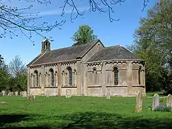 A stone church with a semi-circular chancel and a small bell-cot