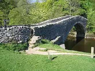 A single-span arched stone bridge over a watercourse