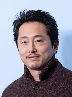 Yeun smiling towards the camera