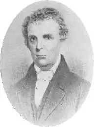 An oval portrait of a friendly looking man with a high forehead looking towards the viewer. His head and shoulders are visible, and his shoulders are turned slightly to the left. His hair is loosely combed, and he is wearing an old-fashioned coat and waistcoat. His shirt is white, with a loose collar and a white stock or cravat.