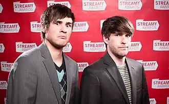 Anthony Padilla standing to the left and Ian Hecox standing to the right in front of a red background which states "Streamy Awards" in a repeating pattern