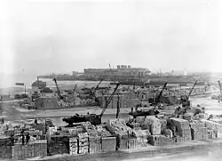 Huge stacks of supplies. Cranes load them onto DUKWs.