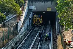 Several workers stand in front of the tunnel entrance.