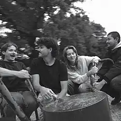 Black-and-white photograph of the four band members on a playground carousel