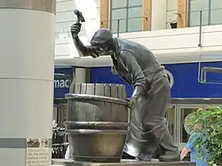 Statue of a cooper hammering a shaping truss over the staves of a barrel