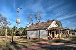 A rural storehouse with a small windmill next to it