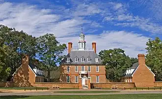 A three-story red brick colonial-style hall and its left and right wings during summer.