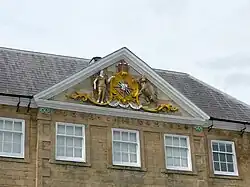 Triangular vertical projection at gutter level with decorative edge mouldings and gilded coat of arms