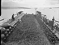 At Scapa Flow, a Royal Navy net laying vessel prepares to lay an anti-submarine net, which is 900 feet (270&nbsp;m) long, weighs over 40 long tons (41&nbsp;t) and could be laid in 4 minutes.