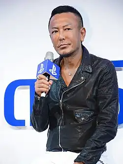 Toshihiro Nagoshi, speaking into a microphone