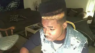 Image 39American teenager with hi-top fade and distressed acid wash denim vest, 2010, showing early 2010s retro revival trends. (from 2010s in fashion)