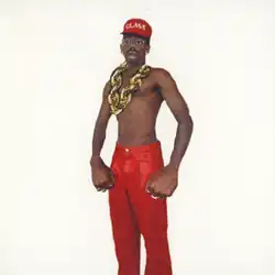 The album cover shows an edited image of Tyler, The Creator with bigger hands, a chain, a red cap reading "GLASS", and a big mouth.
