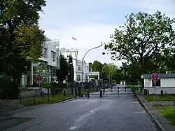 A street with a crossing green fence and a barrier with guard houses.