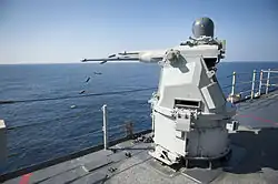 A Mk 38 MOD 2 25 mm autocannon gun system aboard the amphibious dock landing ship USS&nbsp;Pearl Harbor forward ejecting the spent casings.