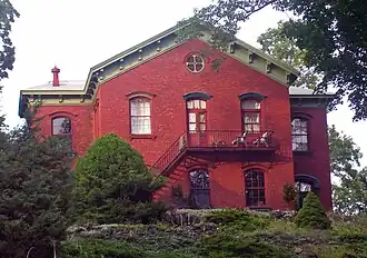 A brick building with pointed roof and landscaped lawn
