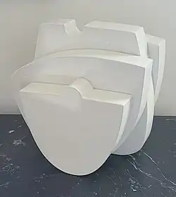 A small white, table top sculpture in a minimalist style.