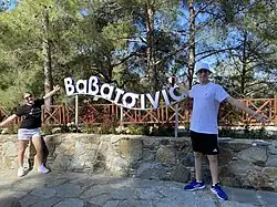 A Sign from the Village of Vavatsinia. 2 Tourist children are next to it.