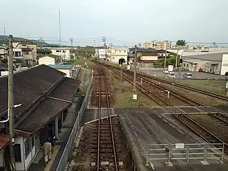 A view from the island platform. There is a level crossing connecting the station building (left) to the island platform and, beyond, to the side platform.