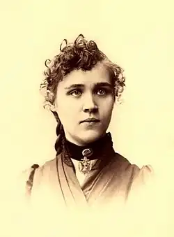 Portrait photograph of Voltairine de Cleyre, wearing a dress and short curly hair