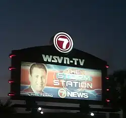 A stylized outdoor marquee sign with the "Circle 7" logo on top and "WSVN-TV" underneath. Below that is a billboard with a picture of Phil Ferro to the left (with his name below) and text to the right, "THE STORM STATION 7 NEWS"