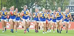 A group of female Australian rules footballers jogging together