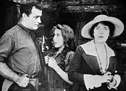 Black and white film still showing three people in period costume