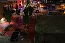 People gather around piled flowers, candles, and signs memorializing Knajdek