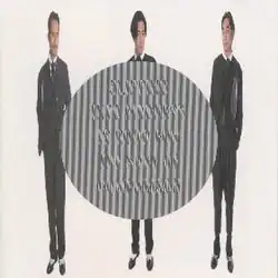 A horizontally compressed photo of the band dressed in suits, with a diffraction grating circle in the middle with the English text "Slipping into madness is good for the sake of comparison".